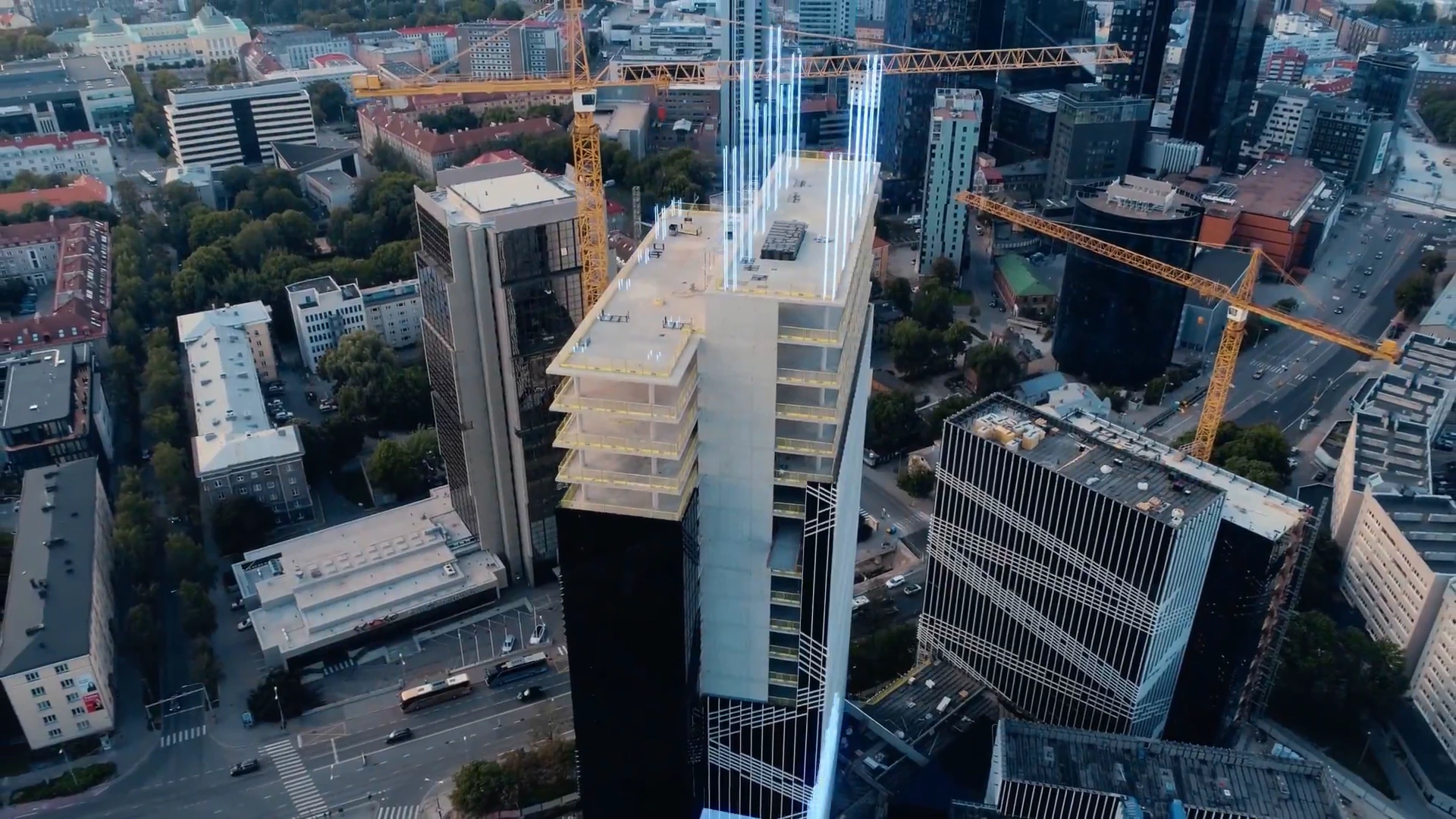 Aerial view of a city where a new building rises as a digital model beside construction cranes